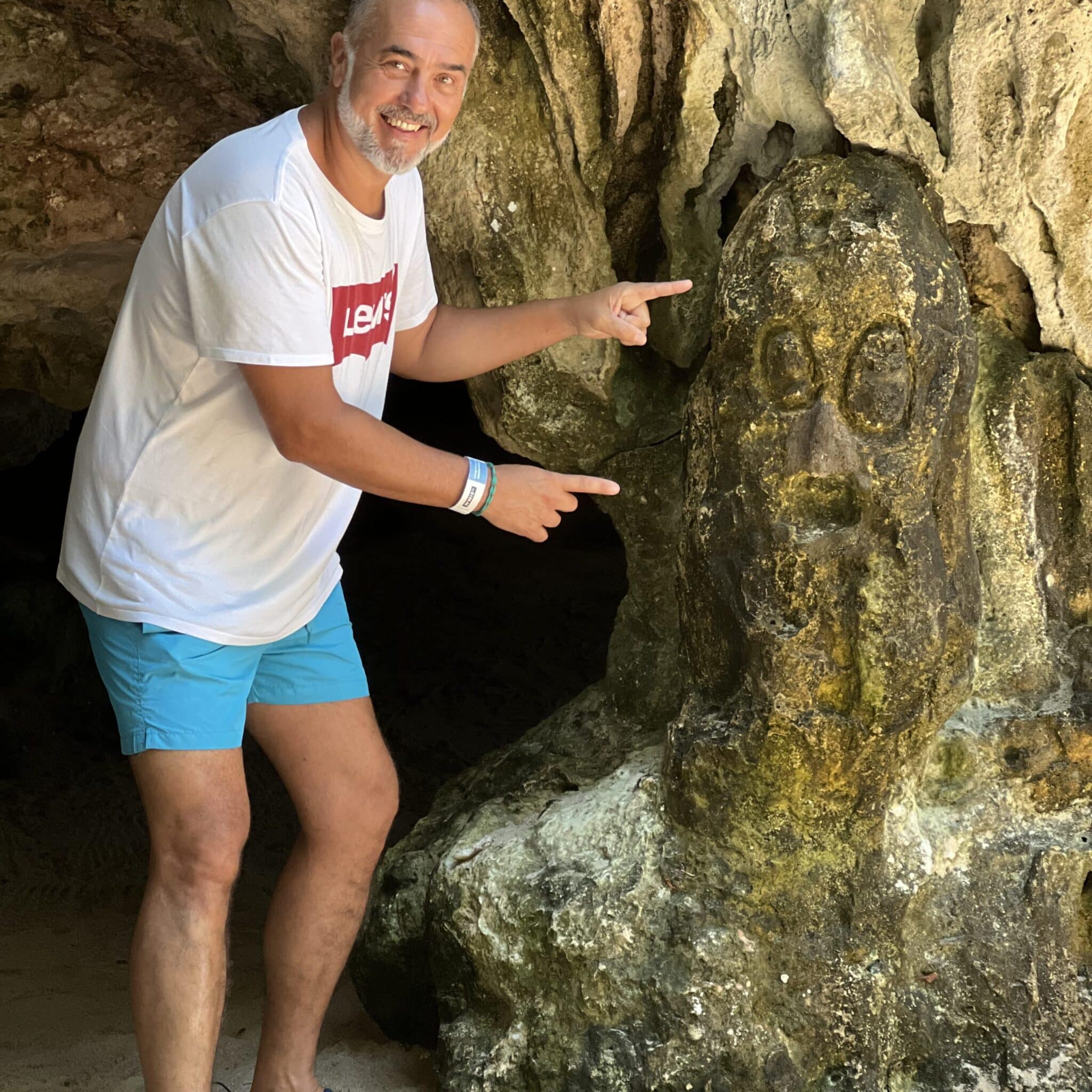 Man pointing at a sculpture in a cave
